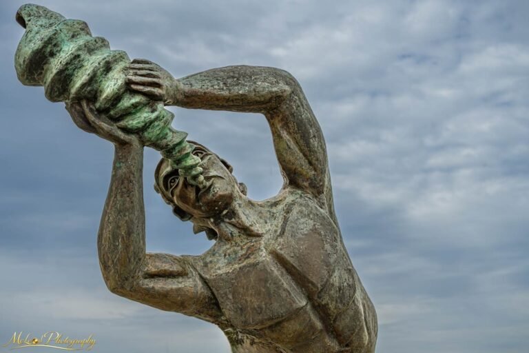 Bronze Triton Statue Blowing Conch Shell Against Moody Sky