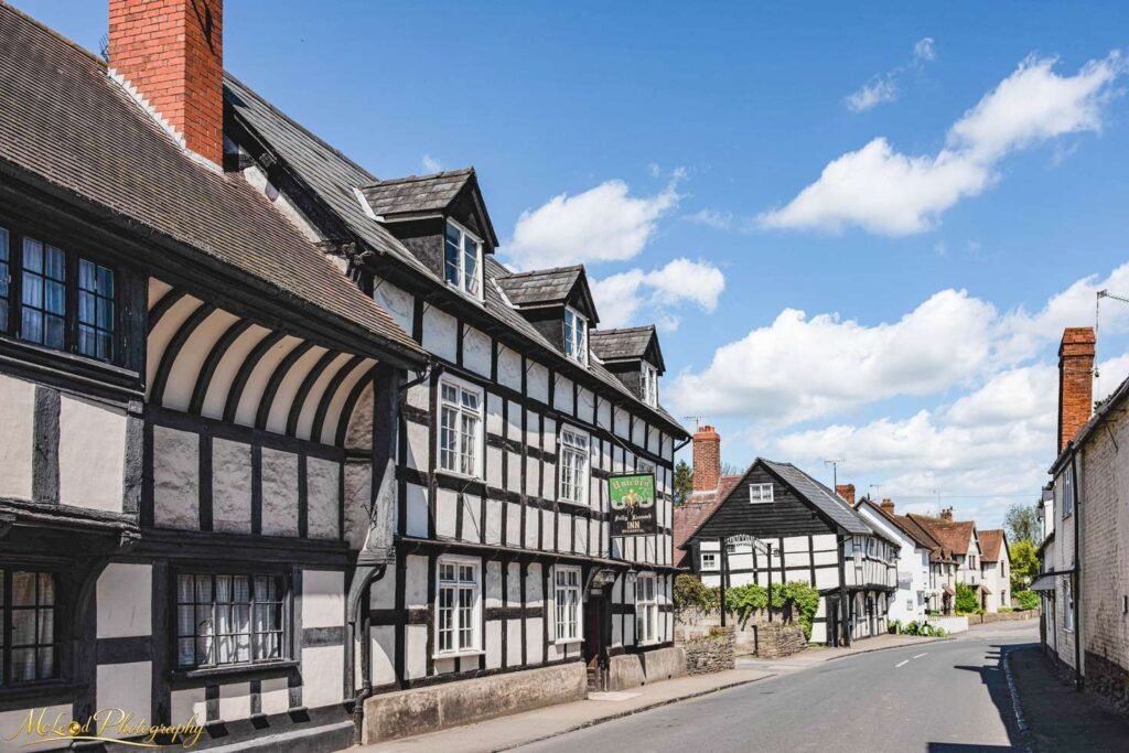 Historic Tudor Village Street with Timber-Framed English Inn — Fine art canvas print by Naomi McLeod