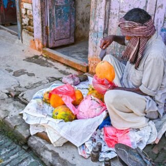 Indian Street Vendor Selling Papayas Against Pastel Walls