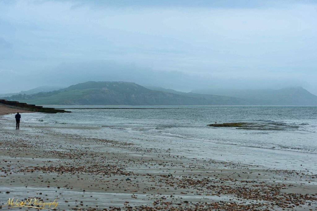 Misty Welsh Coastline with Lone Figure on Pebble Beach — Fine art canvas print by Naomi McLeod