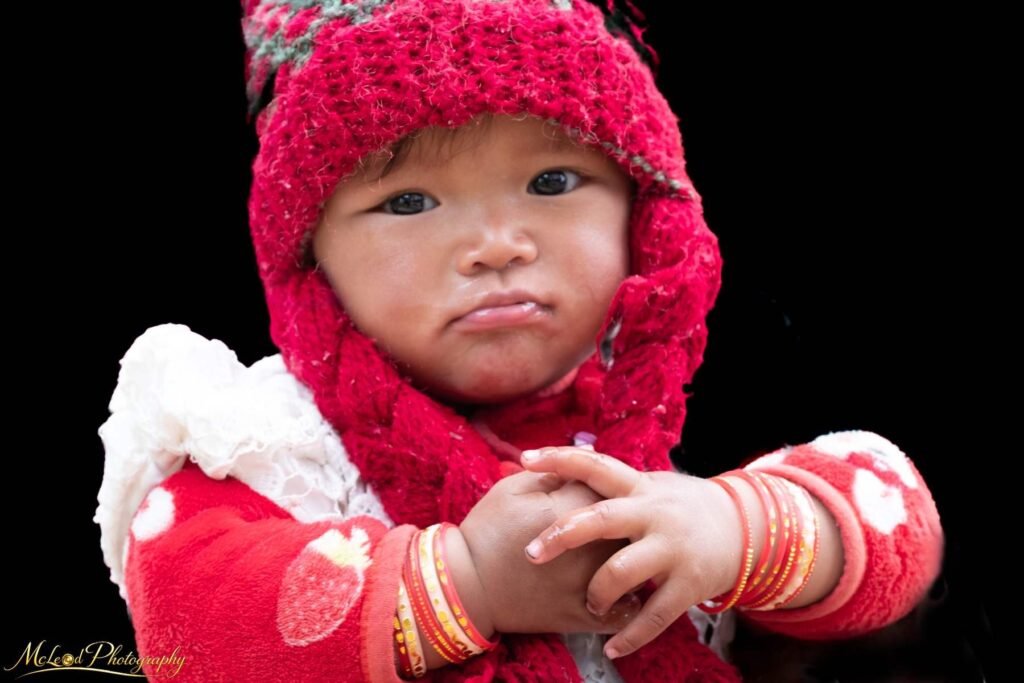 Adorable Nepalese Baby in Traditional Red Knitted Hat — Fine art canvas print by Naomi McLeod
