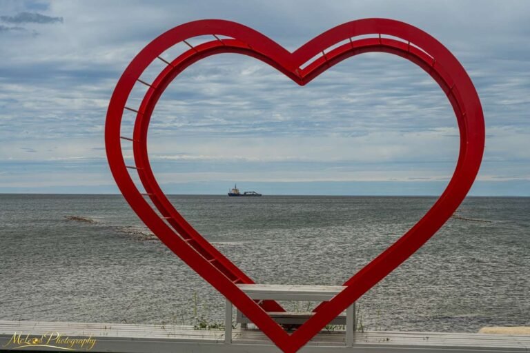 Red Heart Sculpture Framing Ocean Ship – Romantic Coastal Art