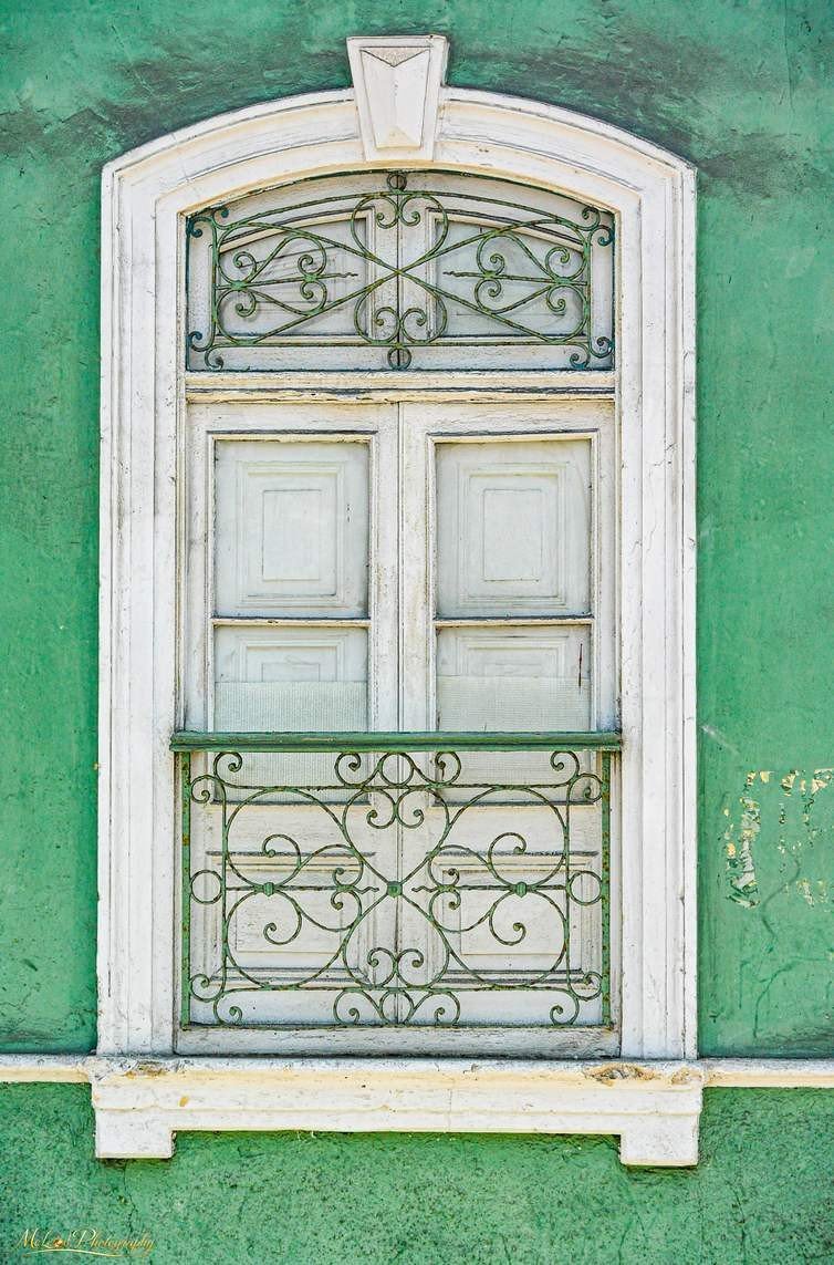 Colonial Window with Ornate Ironwork on Green Wall