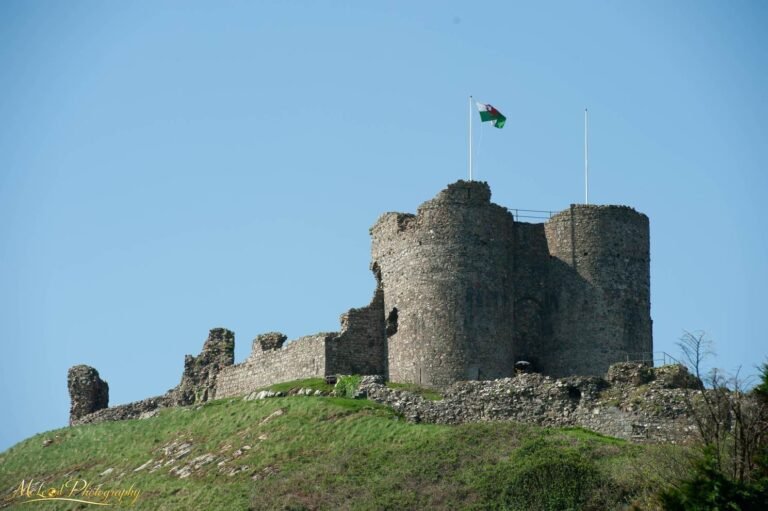 Ancient Welsh Castle Ruins with Dragon Flag on Green Hill